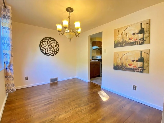 unfurnished room featuring visible vents, baseboards, a notable chandelier, and wood finished floors