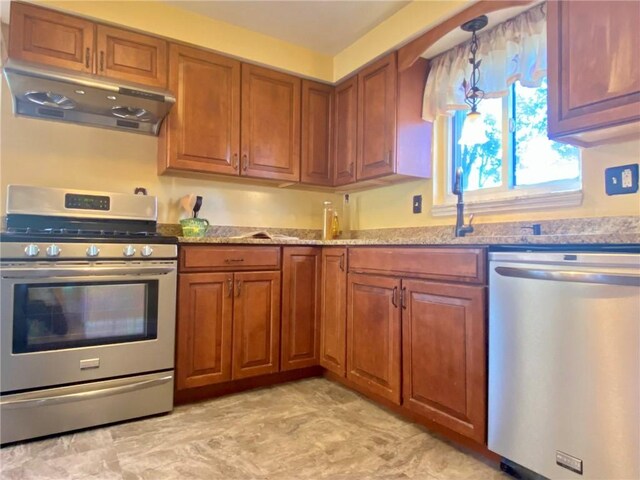 kitchen featuring pendant lighting, brown cabinetry, under cabinet range hood, and stainless steel appliances