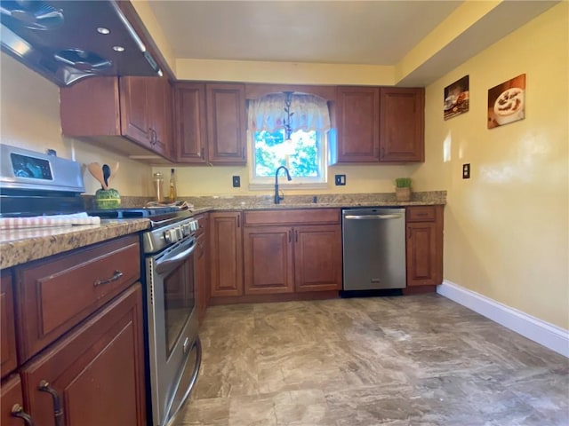 kitchen with light stone countertops, a sink, stainless steel appliances, extractor fan, and baseboards