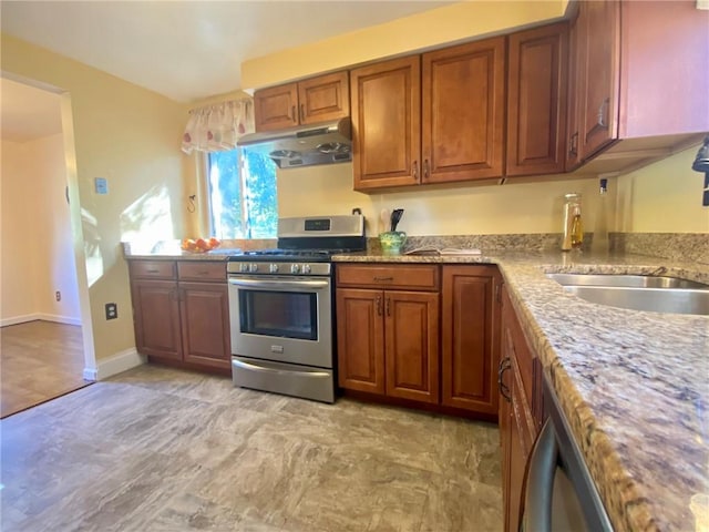 kitchen featuring a sink, brown cabinetry, stainless steel gas range oven, and under cabinet range hood
