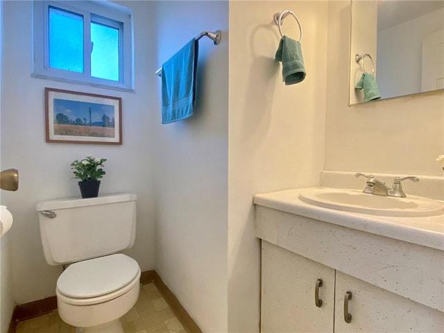 bathroom featuring toilet, vanity, and baseboards