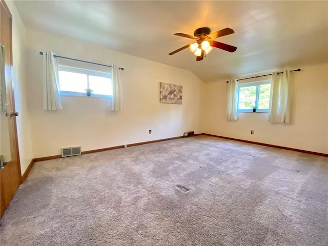 carpeted empty room with visible vents, ceiling fan, vaulted ceiling, and baseboards