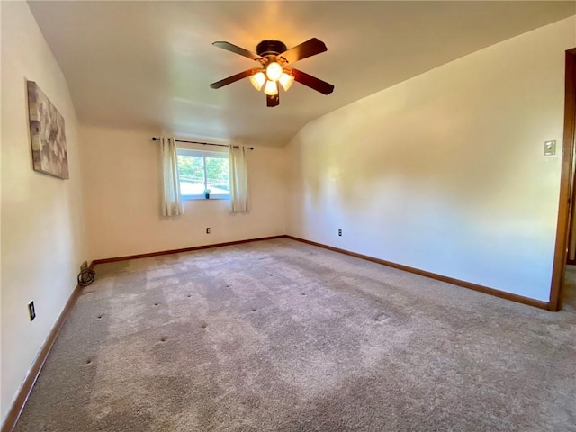 carpeted empty room with baseboards, a ceiling fan, and vaulted ceiling