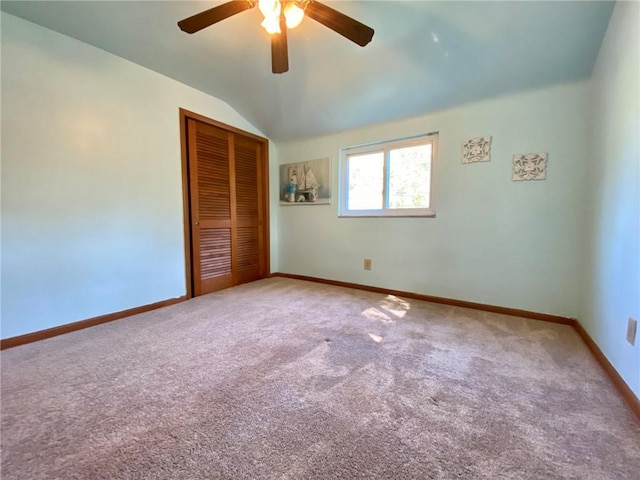 unfurnished bedroom with a closet, baseboards, ceiling fan, carpet floors, and vaulted ceiling
