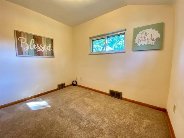 carpeted empty room featuring visible vents, baseboards, and vaulted ceiling