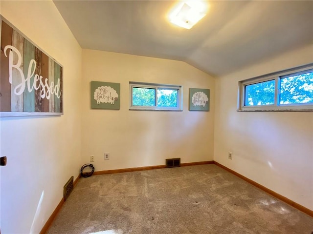 carpeted spare room featuring visible vents, baseboards, and lofted ceiling