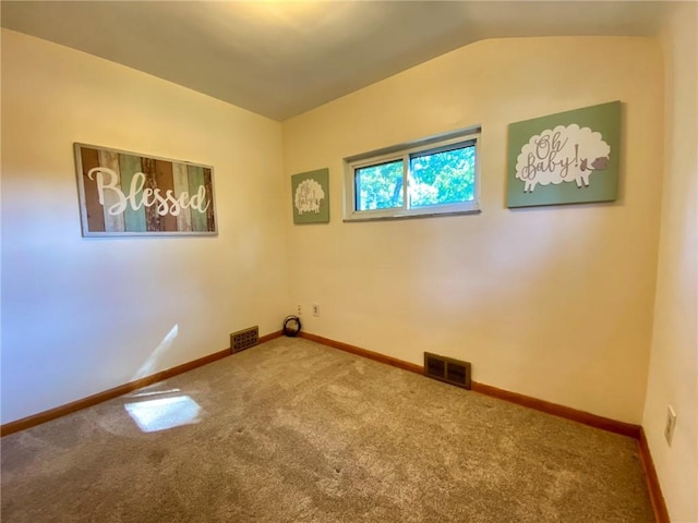 carpeted spare room featuring visible vents, baseboards, and vaulted ceiling