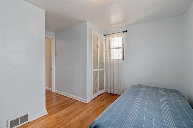bedroom featuring visible vents, baseboards, and wood finished floors