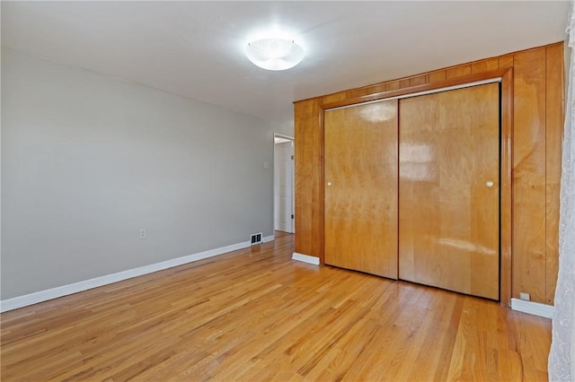 unfurnished bedroom with a closet, light wood-style floors, baseboards, and visible vents