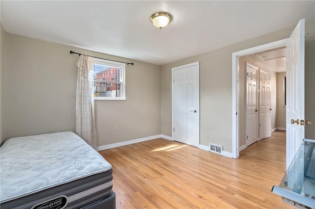 bedroom featuring visible vents, light wood-style flooring, and baseboards