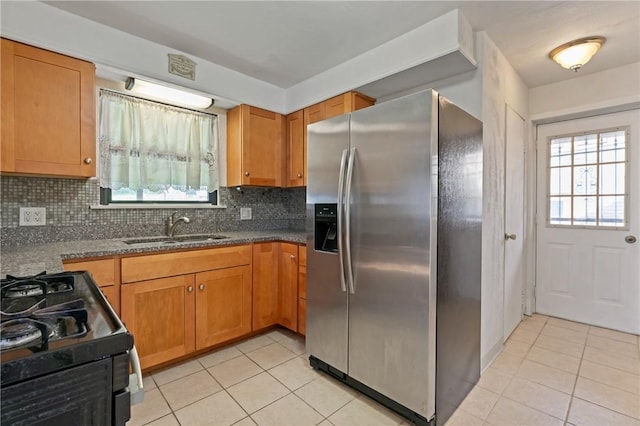 kitchen with a sink, a wealth of natural light, stainless steel fridge, and light tile patterned flooring