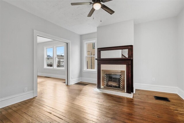 unfurnished living room featuring visible vents, baseboards, a ceiling fan, and hardwood / wood-style floors