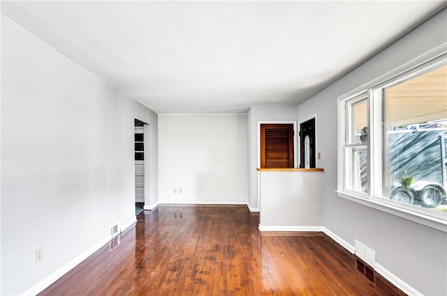 unfurnished room featuring visible vents, baseboards, and wood finished floors