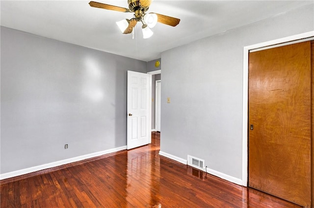 unfurnished room featuring baseboards, wood finished floors, visible vents, and a ceiling fan