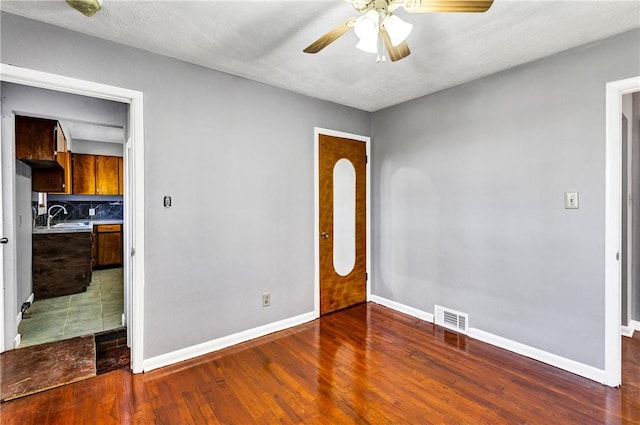 unfurnished room featuring wood finished floors, visible vents, baseboards, and ceiling fan