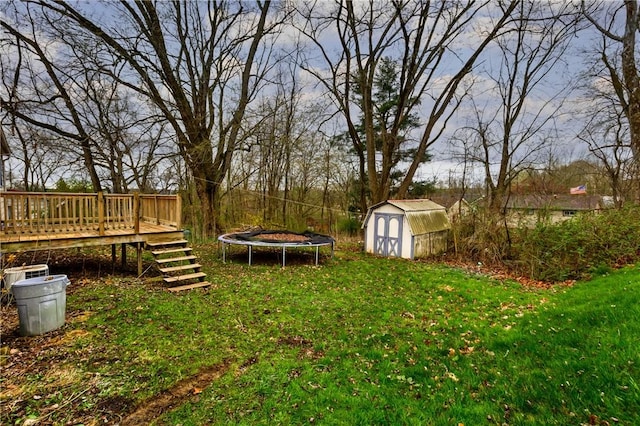 view of yard featuring a wooden deck, a storage unit, an outdoor structure, and a trampoline