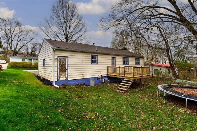 rear view of property with central air condition unit, a wooden deck, a trampoline, a lawn, and stairway