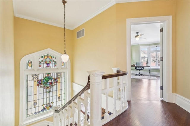 interior space featuring dark wood finished floors, ornamental molding, visible vents, and an upstairs landing