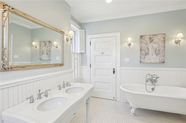 full bath with a freestanding tub, a sink, and a wainscoted wall
