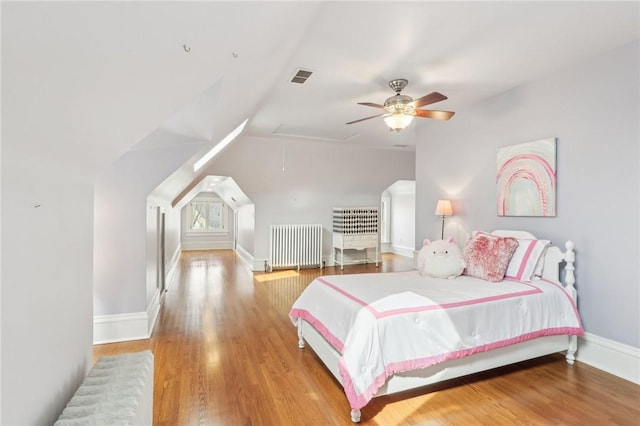 bedroom featuring visible vents, baseboards, radiator, and wood finished floors