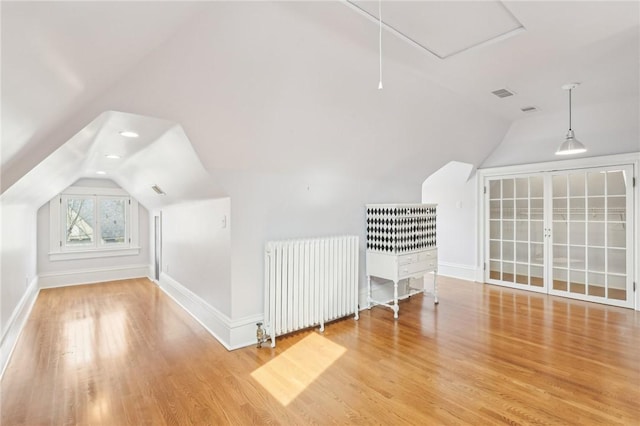 bonus room featuring radiator heating unit, visible vents, wood finished floors, lofted ceiling, and baseboards