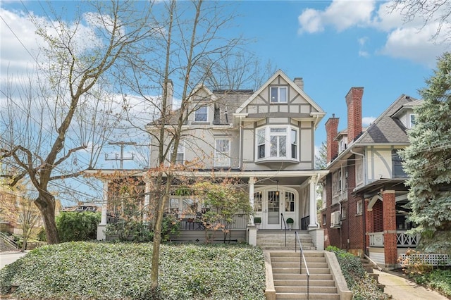 view of front facade featuring french doors, stairway, covered porch, and stucco siding