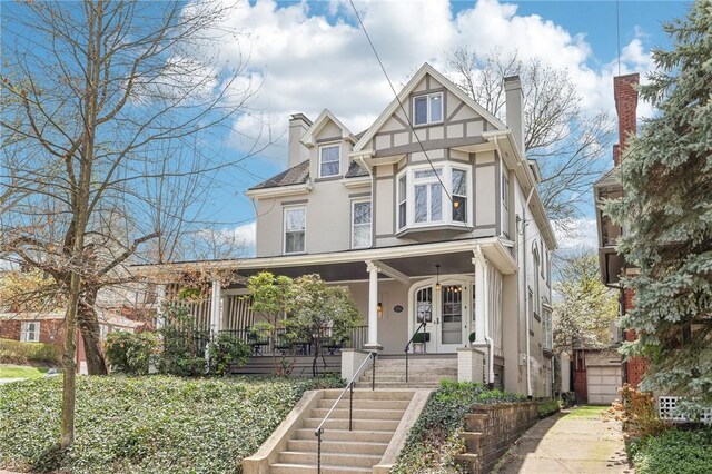 view of front of property with a chimney, covered porch, stucco siding, and stairway