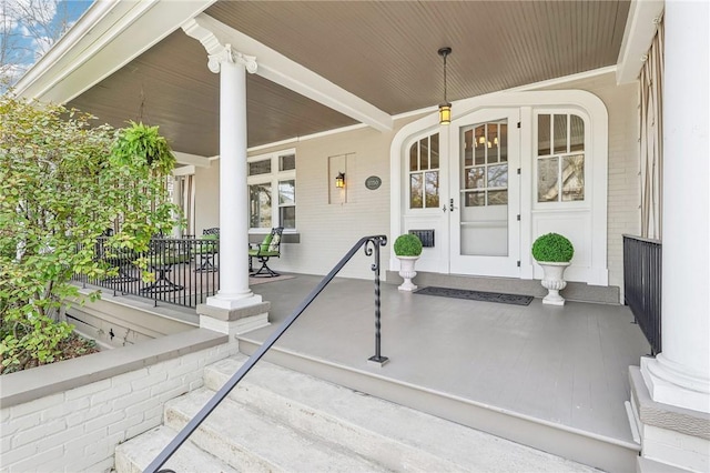 view of exterior entry featuring a porch and brick siding