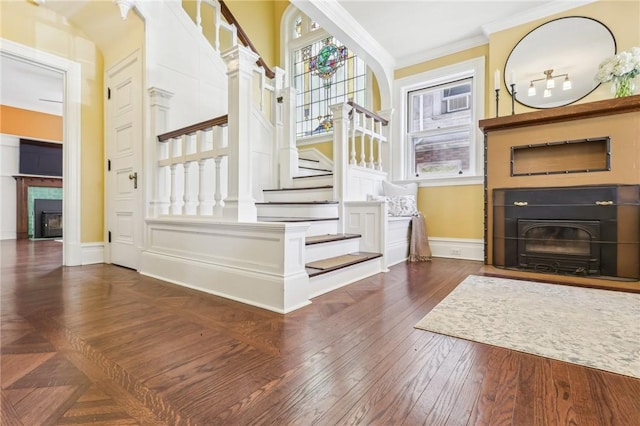 stairs featuring ornamental molding, baseboards, wood finished floors, and a fireplace with flush hearth
