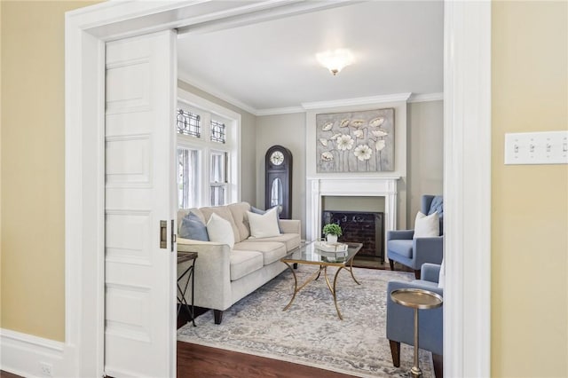 living room featuring a fireplace with flush hearth, crown molding, and wood finished floors