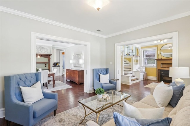 living area featuring dark wood finished floors, ornamental molding, and stairway