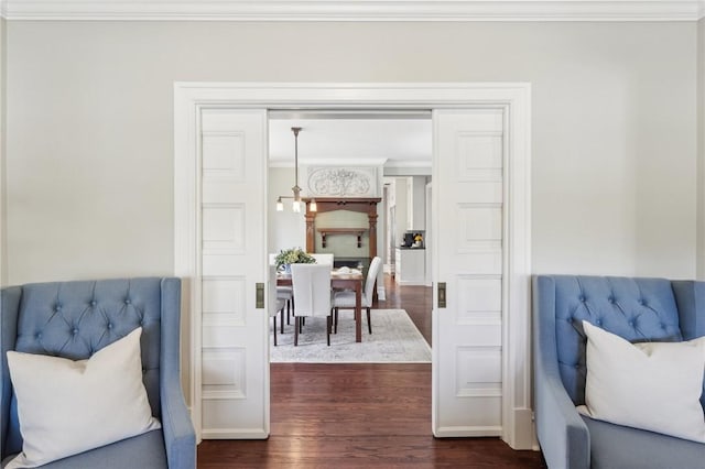 sitting room featuring baseboards, crown molding, and dark wood finished floors