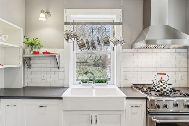 kitchen featuring a sink, dark countertops, wall chimney exhaust hood, and high end stove