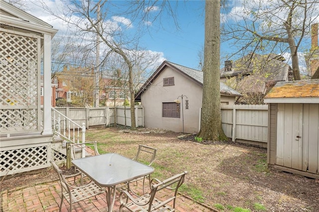 view of yard featuring an outbuilding, a fenced backyard, and outdoor dining area