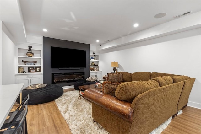 living area with visible vents, built in features, and light wood finished floors