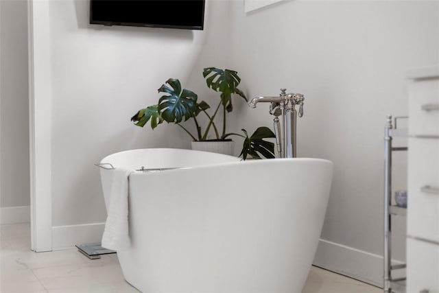full bath with marble finish floor, baseboards, and a soaking tub