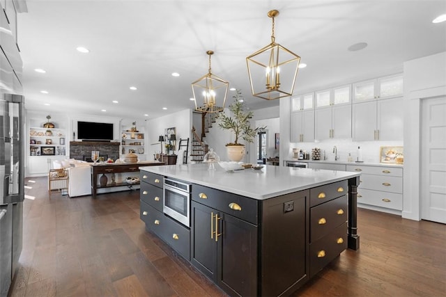 kitchen with dark wood-style floors, stainless steel microwave, light countertops, and white cabinetry