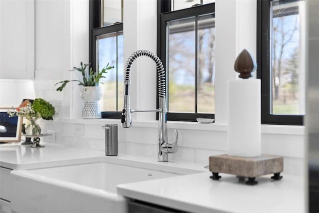 room details featuring a sink, light countertops, and white cabinets
