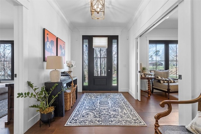 foyer featuring ornamental molding, baseboards, an inviting chandelier, and wood finished floors