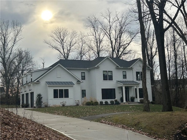traditional-style home featuring driveway, a standing seam roof, a front lawn, and metal roof