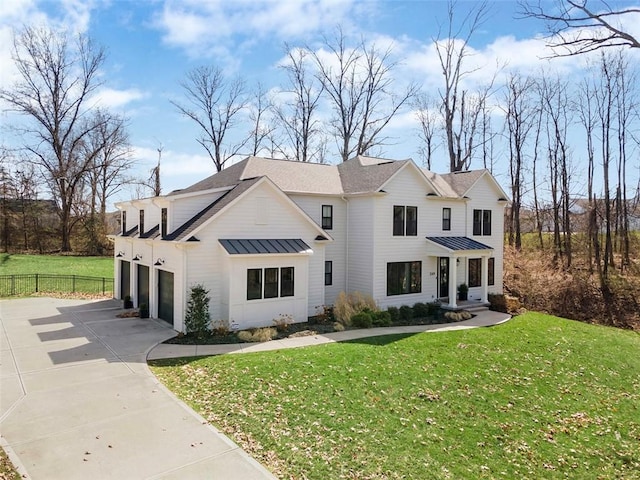 modern farmhouse style home featuring driveway, a front yard, a standing seam roof, metal roof, and fence