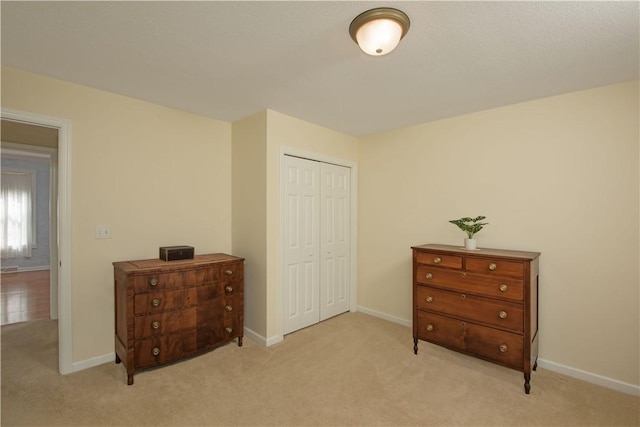 bedroom featuring baseboards, a closet, and light colored carpet