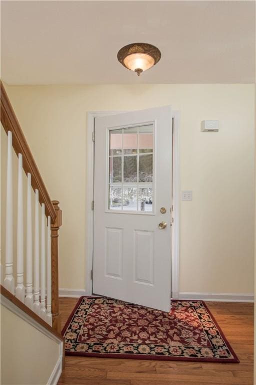foyer featuring baseboards, wood finished floors, and stairs