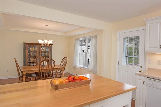 dining room featuring baseboards, a raised ceiling, and a notable chandelier