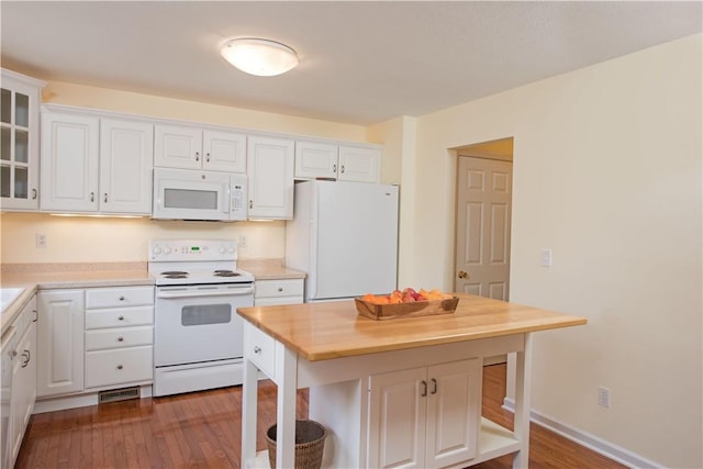 kitchen featuring white appliances, glass insert cabinets, white cabinetry, a breakfast bar, and butcher block countertops