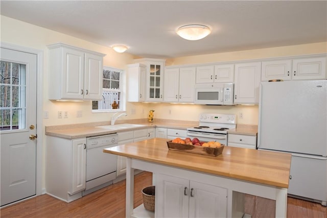 kitchen featuring glass insert cabinets, a sink, white appliances, light wood-style floors, and white cabinetry