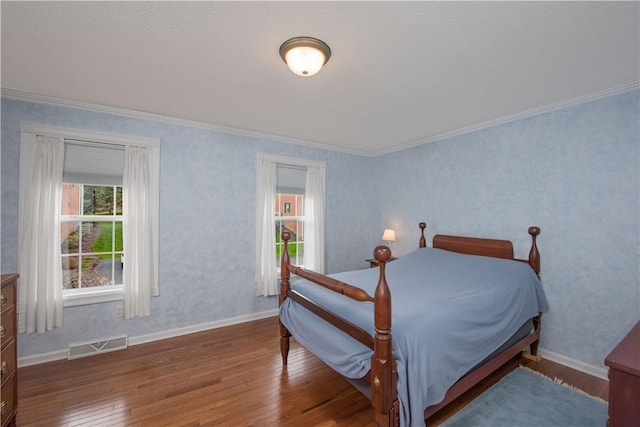 bedroom with visible vents, hardwood / wood-style flooring, baseboards, and ornamental molding