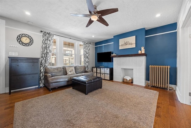 living room with a textured ceiling, radiator, ceiling fan, and wood finished floors