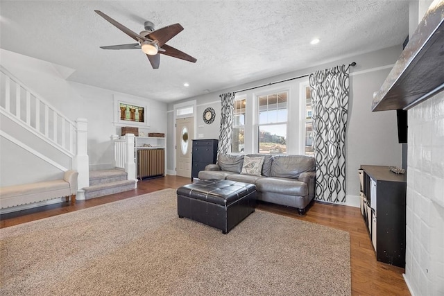 living room with stairs, a textured ceiling, a ceiling fan, and wood finished floors