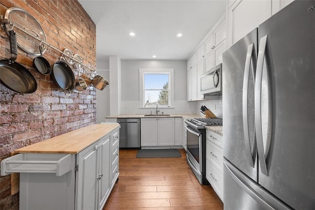 kitchen with dark wood-style flooring, recessed lighting, white cabinetry, stainless steel appliances, and a sink